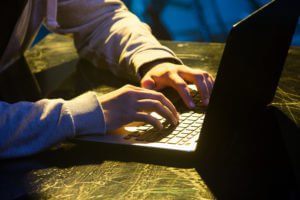 photodune 20358426 hooded computer hacker stealing information with laptop xxl 300x200 1 1
