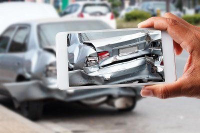 un smartphone prenant une photo des dégâts causés par un accident de voiture